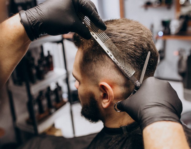 Client doing hair cut at a barber shop salon